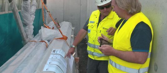 Material Management App wird von zwei Mitarbeitern auf der Baustelle verwendet, um QR-Code auf Packliste zu scannen.