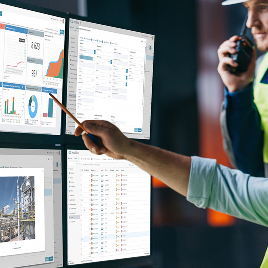 Site manager discussing project progress on four screens displaying Insite LMS, the platform for industrial construciton.