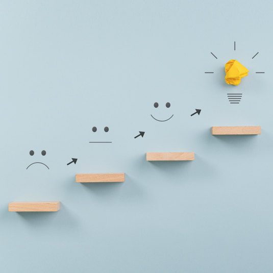 Symbolic representation from resistance to flow (wooden staircase with smileys and light bulb at the end).