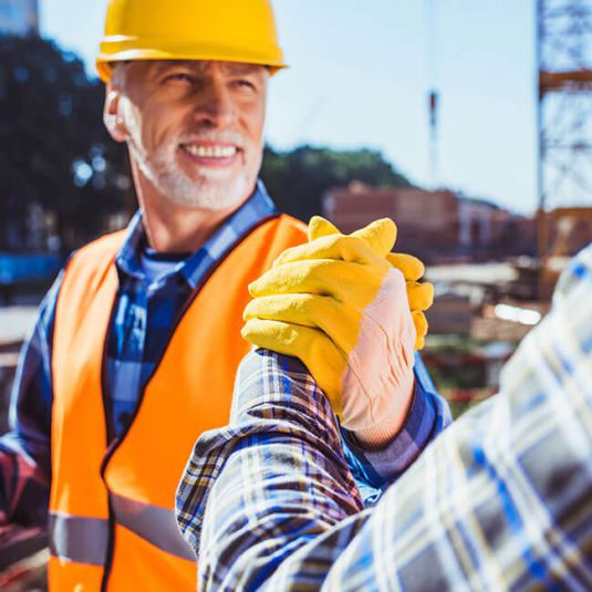 Industrieanlagenbau 2022: Transparente Zusammenarbeit fördert Projekterfolg. Industrieanlagenbau: Zwei Arbeiter auf der Baustelle beim Handschlag.