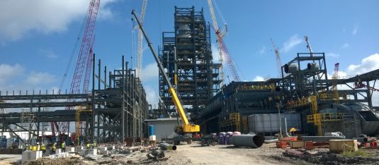 Anlagenbau: Baustelle mit Arbeitsfahrzeugen, Material und Installationsarbeiten.
