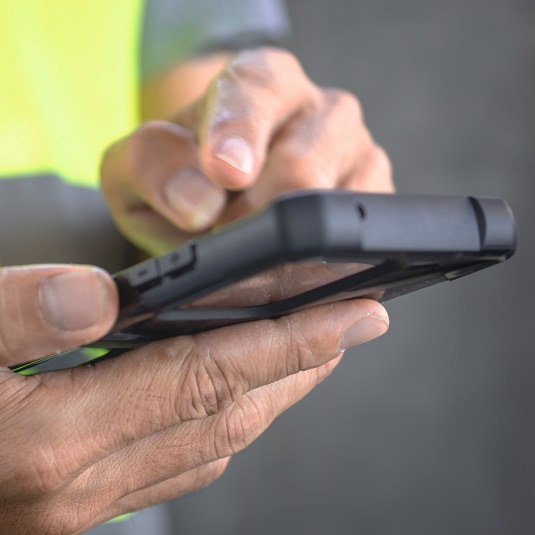 Material Tracking Software ohne Hardware-Barrieren! Insite LMS kann via App auf Smartphones genutzt werden. Robustes Handy in den Händen eines Bauarbeiters.