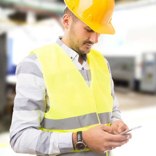 Bauleiter mit Mobiltelefon und gelbem Schutzhelm.